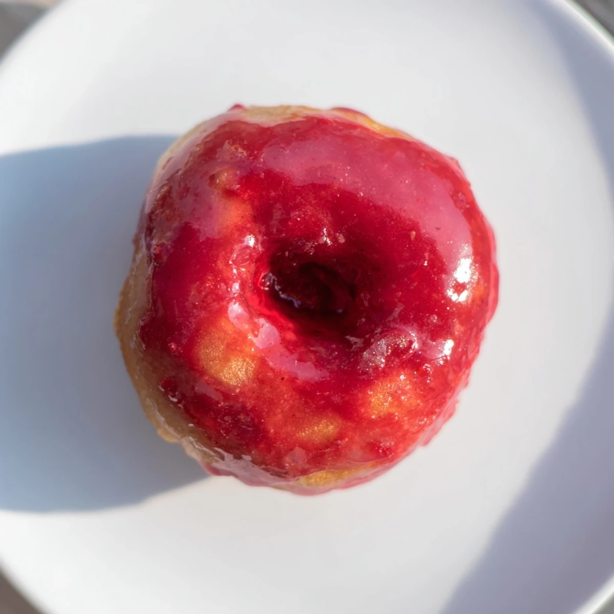 Golden-brown mini pączki holes gleaming, coated in a bright cherry glaze, ready to be enjoyed.