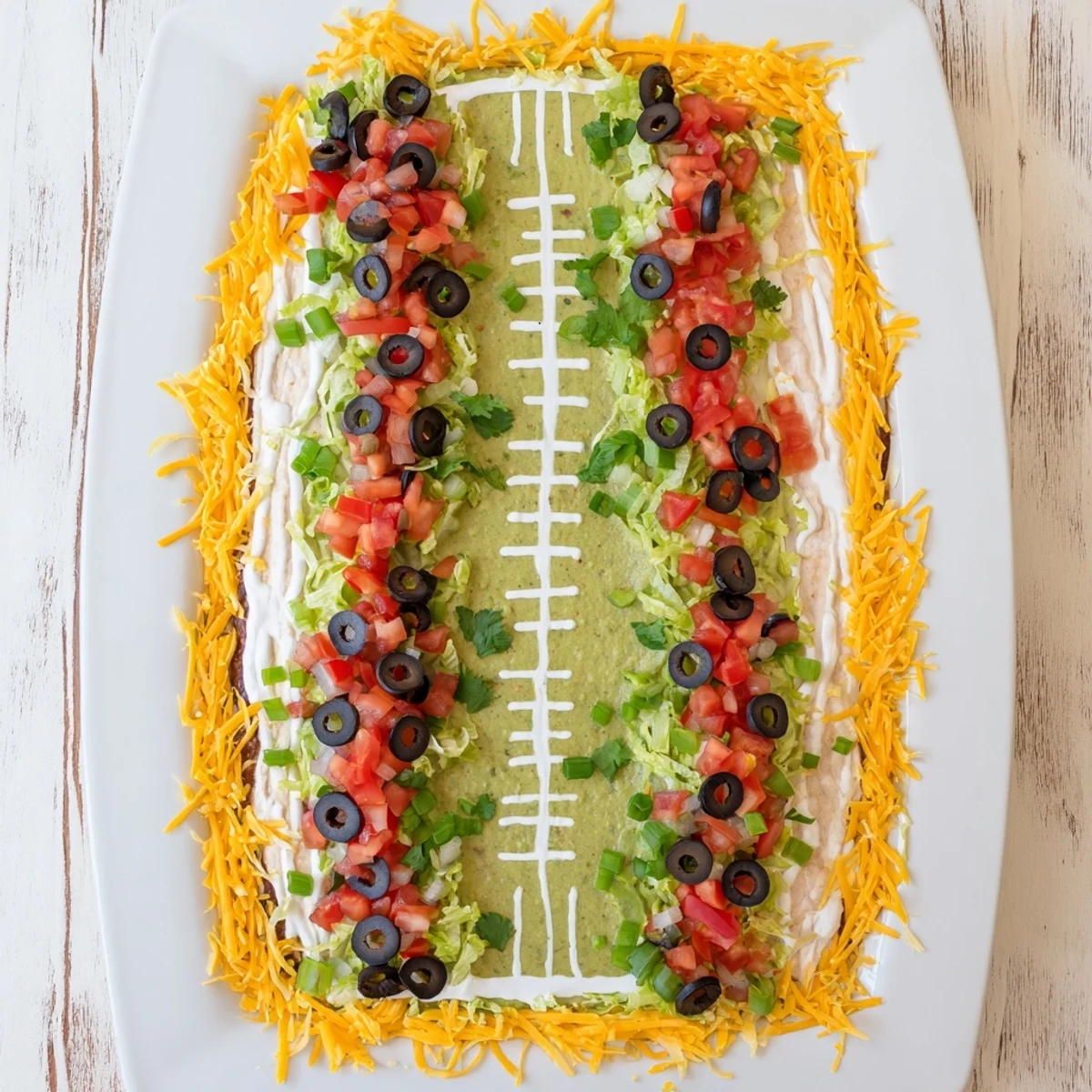 Football Field Dip platter, a creamy layered appetizer with vibrant colors and fun toppings.