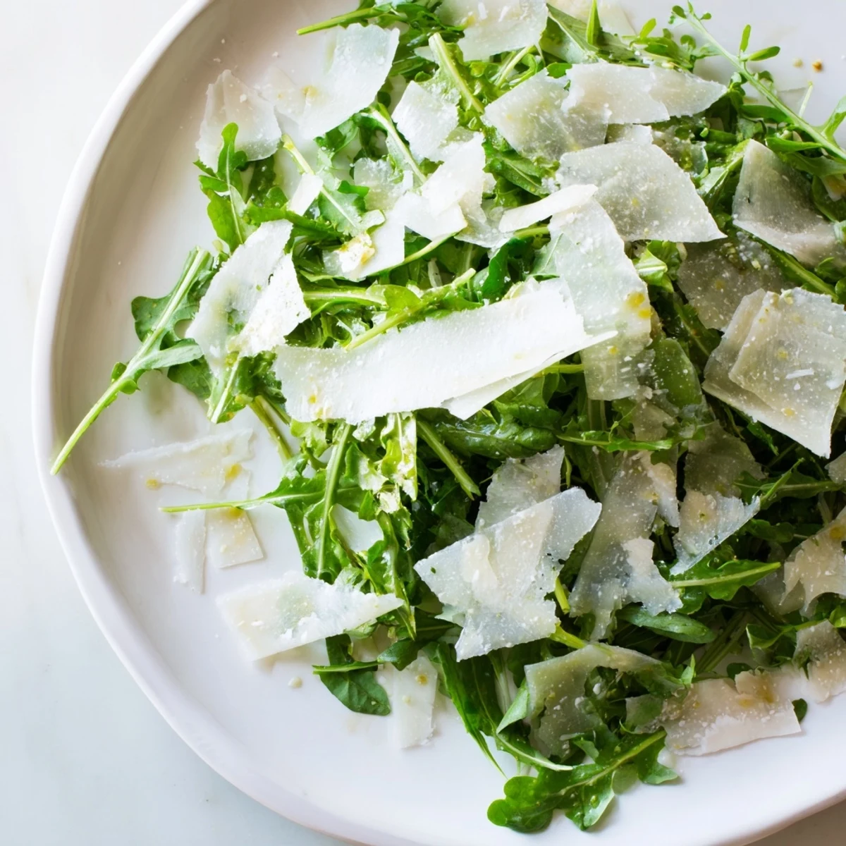 Enjoy this light and flavorful arugula salad; the lemon dressed greens are topped with delicate Parmesan.