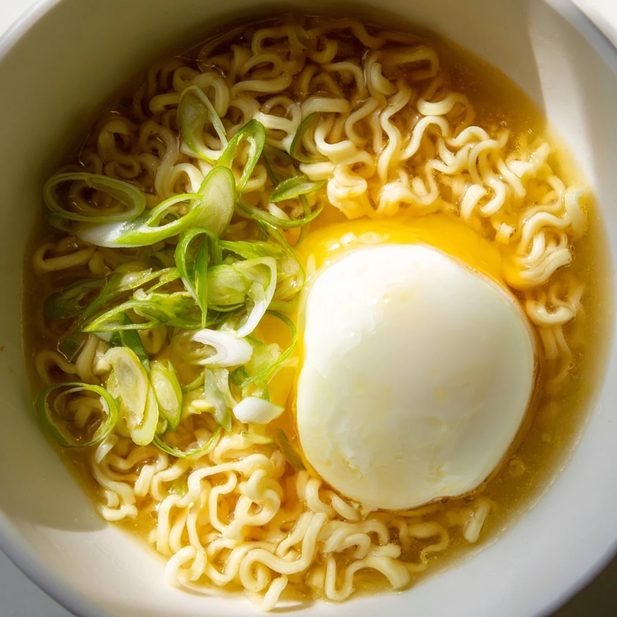 Steaming bowl of upgraded instant ramen, featuring a soft egg and vibrant scallions, ready to eat.