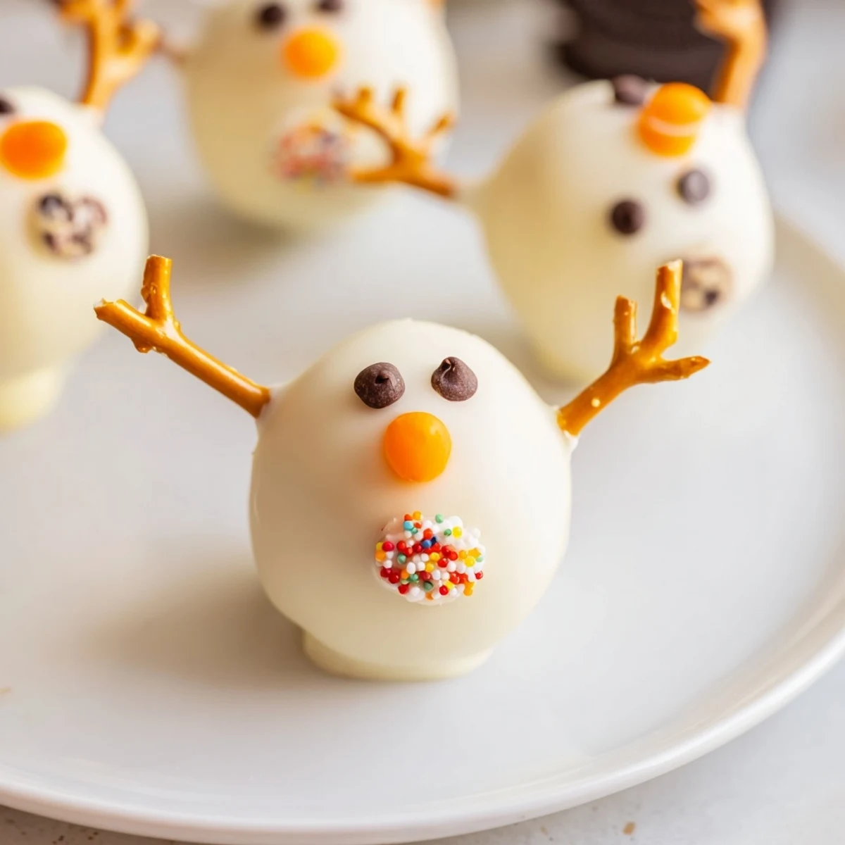 Close-up of adorable Oreo Snowman Cake Pops, coated in white chocolate and ready to enjoy.