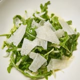 This vibrant arugula salad features peppery greens coated in tangy lemon dressing, a quick, easy Italian dish.