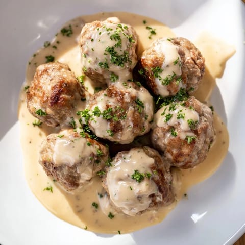A close-up of tender German meatballs, glistening with gravy, offering a comforting, savory aroma.