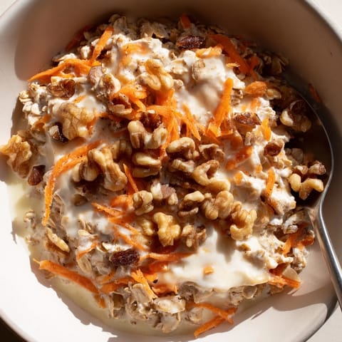 A vibrant bowl of Carrot Cake Overnight Oats, showcasing grated carrots and a cinnamon spice aroma.