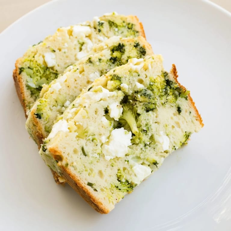 Golden broccoli and feta loaf cooling on a wire rack, garnished with fresh dill and pepper, perfect for lunch.