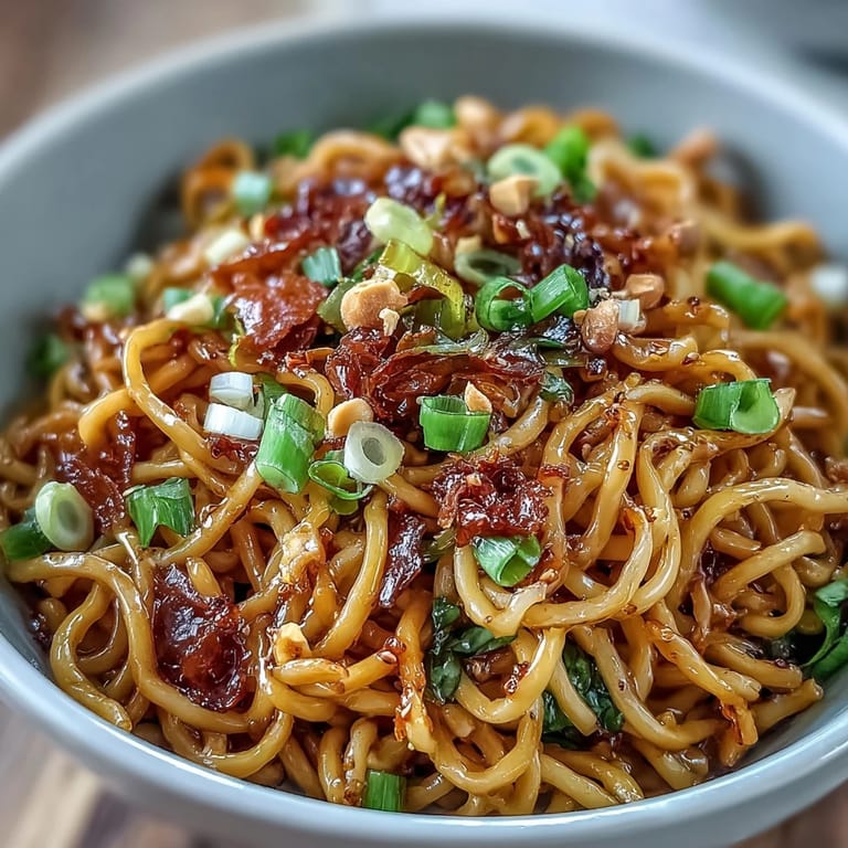Vibrant chili crisp noodles with sautéed garlic and crisp-tender vegetables, served steaming hot for a bold, savory meal.